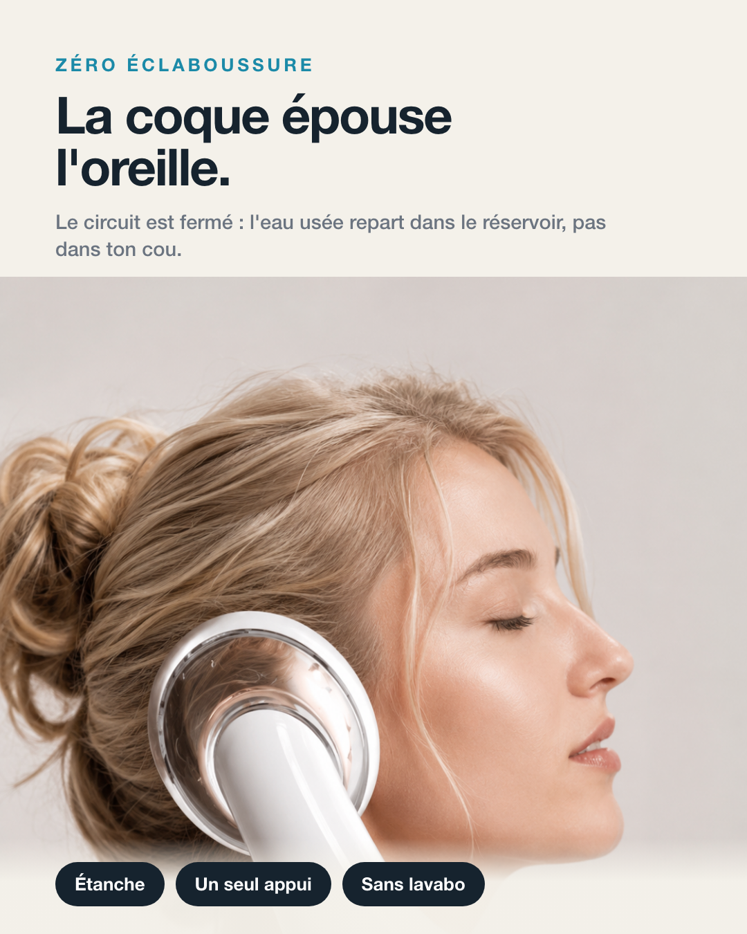 La coque épouse l’oreille : le circuit est fermé, l’eau usée repart dans le réservoir et pas dans le cou. Une femme tient l’appareil posé contre son oreille, les yeux fermés. Étanche, un seul appui, sans lavabo.